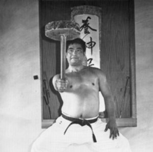 Karateka training with a chi ishi, a traditional stone-weighted lever