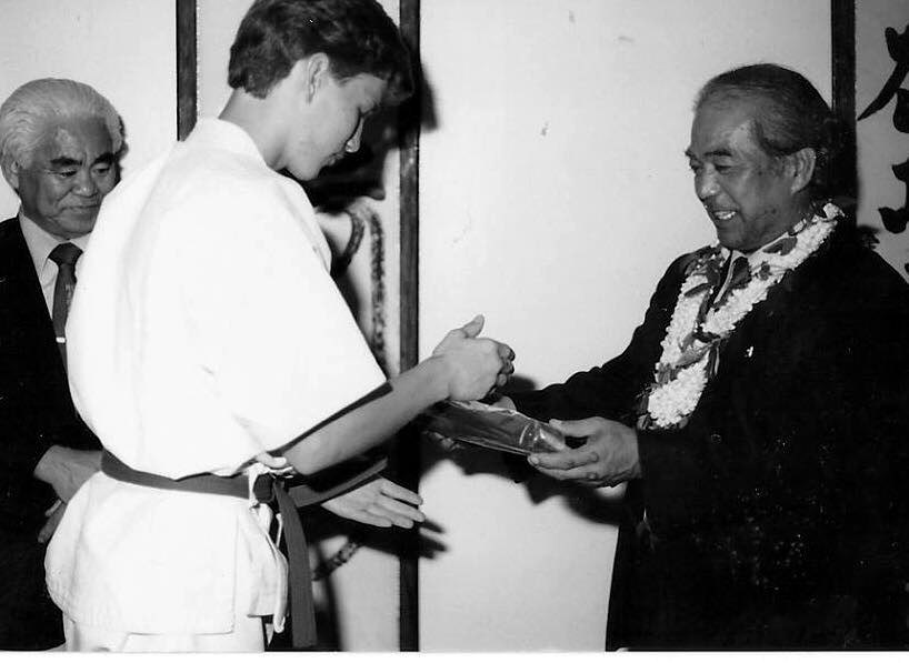 Young Sensei Walker in a green belt receiving a new belt from Masanobu Shinjo